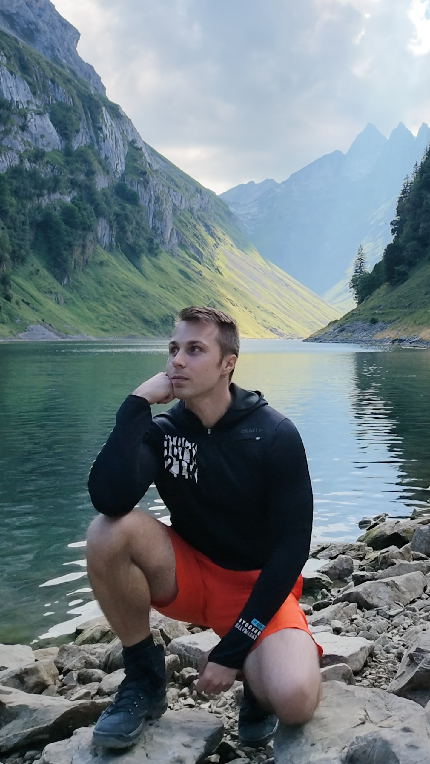 Nicolas Maier am Ufer eines Bergsees vor einer grünen Berglandschaft